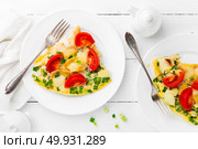 Omelet. Eggs fried. Scrambled eggs with green onion and fresh tomato. Omlette on white plate. Breakfast. Top view. White wooden background. Стоковое фото, агентство Ingram Publishing / Фотобанк Лори