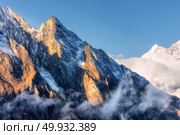 Majestical scene with mountains with sunlit peaks in clouds in Nepal. Landscape with beautiful high rocks and blue sky in sunny bright day. Nature background. Travel. Amazing Himalayas. Стоковое фото, агентство Ingram Publishing / Фотобанк Лори