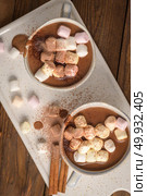Cups of hot chocolate drink with marshmallows and cinnamon on brown wooden background. Стоковое фото, агентство Ingram Publishing / Фотобанк Лори
