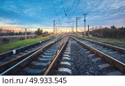 Railroad at sunset. Railway station against blue sky. Industrial landscape with railroad, cloudy sky, green grass, trees. Railway junction. Heavy industry. Cargo shipping. Freight transoprtation. Railroad at beautiful sunset. Railway station. Стоковое фото, агентство Ingram Publishing / Фотобанк Лори