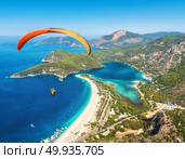 Paragliding in the sky. Paraglider tandem flying over the sea with blue water and mountains in bright sunny day. Aerial view of paraglider and Blue Lagoon in Oludeniz, Turkey. Extreme sport. Landscape. Paraglider tandem flying over the sea with blue water and mounta. Стоковое фото, агентство Ingram Publishing / Фотобанк Лори