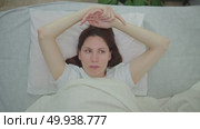 Young adult woman wakes up in the morning in bed and drops her still numb hand after sleeping because of a sleep with an extended arm. Стоковое видео, видеограф Денис Кебедов / Фотобанк Лори