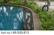 A fragment of a swimming pool. A tropical resort. The blue tiled bottom is visible through the clear water. Green vegetation along the rounded perimeter. Lifebuoy. Mauritius. Hotel. Стоковое фото, фотограф Вера Ивановна Кубарева / Фотобанк Лори