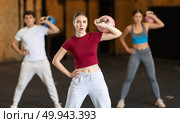 Girl in gym does exercises with kettlebell, lifts and lowers heavy kettlebell with one hand. Стоковое фото, фотограф Яков Филимонов / Фотобанк Лори