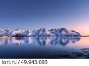 Beautiful snow covered mountains and colorful sky reflected in water at night. Winter landscape with sea, snowy rocks, blue sky, reflection, sunlight at sunset. Lofoten islands, Norway at dusk. Nature. Стоковое фото, агентство Ingram Publishing / Фотобанк Лори