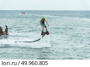 Thailand beach - Phuket - September 30, 2016: An unidentified guy is playing with a new water sport called fly board at bay in Phuket, Thailand. Редакционное фото, агентство Ingram Publishing / Фотобанк Лори