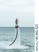 Thailand beach - Phuket - September 30, 2016: An unidentified guy is playing with a new water sport called fly board at bay in Phuket, Thailand. Редакционное фото, агентство Ingram Publishing / Фотобанк Лори