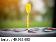 Yellow dart arrow hitting in the center of dartboard. Стоковое фото, агентство Ingram Publishing / Фотобанк Лори