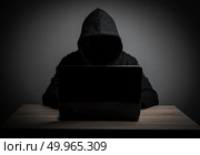 Hacker work front of his laptop computer with dark face. Стоковое фото, агентство Ingram Publishing / Фотобанк Лори