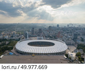 KIEV, UKRAINE - July 19, 2018. Aerial view from drone to a city landscape and National Olimpic Complex in Kiev, Ukraine at sunset on a background cloudy sky in a summer day.. KYIV, UKRAINE - July 19, 2018. National Sports Complex Olympic, stadium NSC Olimpiysky. Panoramic viev from drone of cityscape and the stadium. Редакционное фото, агентство Ingram Publishing / Фотобанк Лори