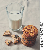 Traditional Christmas treat for Santa - homemade oatmeal cookies with peanut and glass of milk on a textile background, place under text.. The glass of milk with a stack of cookies with chocolate chunks and peanut on a textile towel background, Стоковое фото, агентство Ingram Publishing / Фотобанк Лори