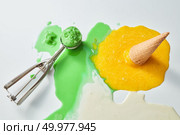 Multicolored splashes of melted ice cream. Scoop of green ice cream and a fallen waffle cone with a yellow ice cream on a blunder background with a copy of the space.Top view. Green and yellow melting ice cream with waffle cone and scoop on white background. Summer concept. Top view. Стоковое фото, агентство Ingram Publishing / Фотобанк Лори