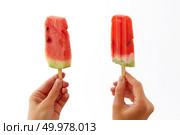 Juicy fresh slices of a watermelon on a stick hold female hands on a white background with a copy space. The concept of healthy berry ice cream lolly or dessert.. Hands of a girl holding two, appetizing, fresh slices of watermelon on a stick on a white background. The concept of healthy homemade ice popsicle with space for text . Summer dessert. Стоковое фото, агентство Ingram Publishing / Фотобанк Лори