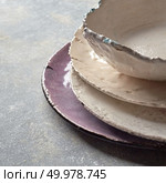 The porcelain dishes handmade on a gray marble table with space under text. Traditional decorative ceramic handcrafted.. Decorative handcrafted pottery - bowls, plates covered with glazed on a gray background with place for text. . Стоковое фото, агентство Ingram Publishing / Фотобанк Лори