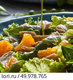 Freshly prepared dietary salad with natural organic vegetables, citrus fruits, chicken with a jet of olive oil falling into a blue ceramic plate.. Close-up of steam of olive oil pours into the salad with natural green vegetables, chicken pieces, orange slices in a blue plate. Стоковое фото, агентство Ingram Publishing / Фотобанк Лори
