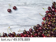Natural organic fruits - ripe juicy red cherry on a gray old wooden background. Top view. Berries frame from freshly picked cherry on wooden gray background with copy space. Стоковое фото, агентство Ingram Publishing / Фотобанк Лори