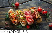 Various of mini bruschetta with tomatoes, salmon, avocado, bacon, and basil butter on wood textured background.. Various of mini bruschetta with tomatoes, salmon, avocado, bacon, and basil butter. Стоковое фото, агентство Ingram Publishing / Фотобанк Лори