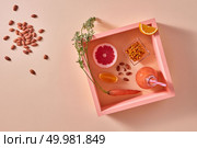Organic drink with sea buckthorn, almonds, citrus fruits in glass on an orange paper in square frame. Healthy dietary food. Flat lay.. Homemade natural organic smoothie, made with grapefruits, orange, berries, carrots and nuts in glass bottle on an orange paper background. Стоковое фото, агентство Ingram Publishing / Фотобанк Лори