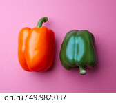 Orange and green peppers on a pink paper background. Organic vegetables. The concept of a healthy diet. Top view. Two different organic peppers on a pink paper background. Vegetarian food. Top view. Стоковое фото, агентство Ingram Publishing / Фотобанк Лори