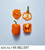 Ripe orange pepper. A set of whole, halved and chopped peppers with a stem on a gray background. Organic Healthy Food. Top view. Set of orange fresh peppers on a gray background. Top view. Стоковое фото, агентство Ingram Publishing / Фотобанк Лори