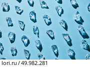 Pattern of pieces of clear glass ice on a blue background with shadows, flat lay. artificial ice cubes on a blue background with shadows. Стоковое фото, агентство Ingram Publishing / Фотобанк Лори