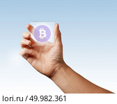 Transparent digital screen is held by a male hand with a bitcoin icon on a blue background. Business, technology and cryptocurrency concept. A man’s hand holds a transparent digital screen with a bitcoin icon ns blue background. Стоковое фото, агентство Ingram Publishing / Фотобанк Лори