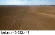 Agricultural landscape, plowed field in spring and forest in the distance against the blue sky, preparation of the earth for sowing works. Photo from the drone. Agricultural ploughed field and soil in spring against the blue sky. Photo from the drone. Стоковое фото, агентство Ingram Publishing / Фотобанк Лори