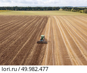 Panoramic view of tractor plowing the soil after harvesting on the field. Aerial view from the drone of the field after harvest. Preparatory work for sowing crops, cultivation of the soil by a tractor after harvesting in the summer time. Стоковое фото, агентство Ingram Publishing / Фотобанк Лори