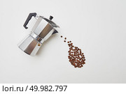 Italian coffee maker and fresh coffee beans in the form of a dripping drop on a white background with copy space. Flat lay. Coffee beans in the form of a drop dripping from a metal coffee maker on a white background with space for text. Concept of morning coffee. Flat lay. Стоковое фото, агентство Ingram Publishing / Фотобанк Лори