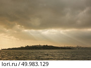 A peaceful beach scene with powerful sun-rays beaming through the clouds with a view of Istanbul. Light of sunbeam through clouds to the sea. Стоковое фото, агентство Ingram Publishing / Фотобанк Лори