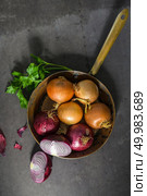 Fresh whole onions in assorted colors and parsley in a small rustic frying pan on kitchen counter top. Стоковое фото, агентство Ingram Publishing / Фотобанк Лори