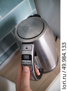 man hand hold the iron electric kettle, preparing hot drink, click on the button on the background of the kitchen. A stylish modern kettle with different temperature selection modes. The possibility of making different teas. metal kettle in the kitchen in the man hand on a kitchen. Стоковое фото, агентство Ingram Publishing / Фотобанк Лори