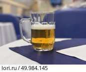 Enjoying a Refreshingly Cold Beer Served in a Mug Elegantly Displayed on a Table Setting. Golden beer served on a wellarranged table captures moments of relaxation and joy with friends and family. Стоковое фото, фотограф worker / Фотобанк Лори