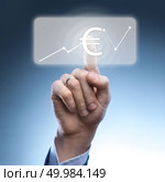 Businessman touched euro currency icon on virtual financial screen.A graph indicating growth.Finance and technology concept.. Businessman touched euro currency icon. Стоковое фото, агентство Ingram Publishing / Фотобанк Лори