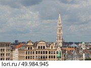 View from a distance the spire of the City hall of Brussels on Grand place square, dark storm clouds hovering over the majestic buildings and the roofs of neighboring houses, Brussels, Belgium. View from a distance the spire of the City hall. Стоковое фото, агентство Ingram Publishing / Фотобанк Лори