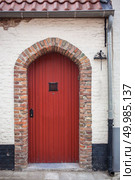 Red door in hause of Bruges, Belgium.. Red door in stone building. Стоковое фото, агентство Ingram Publishing / Фотобанк Лори