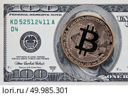 Physical version of gold Bitcoin on the one hundred american dollars. Business, finance, technology concept of worldwide new cryptocurrency and digital maoney. Golden bitcoin on one hundred dollar bills background. Стоковое фото, агентство Ingram Publishing / Фотобанк Лори