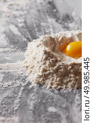 Yolk in organic flour on the kitchen table. Ingredients for home baking. Fresh egg and flour on the kitchen table. Preparation for kneading the dough. Стоковое фото, агентство Ingram Publishing / Фотобанк Лори