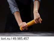 female hands clenching in fists bend, trying to break in half a bunch of raw long yellow thin spaghetti pasta on a black background. chef in an apron breaks a handful of raw Italian spaghetti. Стоковое фото, агентство Ingram Publishing / Фотобанк Лори