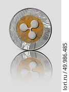 Coin ripple. The front side of the ripple coin is reflected on a white glossy background.. Coin ripple on white glossy background. Conceptual image for worldwide cryptocurrency and digital payment system. Стоковое фото, агентство Ingram Publishing / Фотобанк Лори