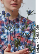 Cute young woman holding beautiful blue eringium flowers. Holiday. Beautiful flower eryngium in a girl’s hand. Стоковое фото, агентство Ingram Publishing / Фотобанк Лори