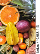 Fresh juicy tropical fruits as a backgraund. Passion fruit, carambola, litchi, kumquat, orange halves, phisalis on a green leaves. Close-up. Top view. Concept of healthy dieting food.. Natural organic background from exotic fruits carambola, half of orange, passion fruit, pineapple leaf in the drops water. Close-up. Стоковое фото, агентство Ingram Publishing / Фотобанк Лори