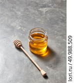 Sweet flower natural honey in a jar and wooden spoon on a gray concrete table, place for text . Rosh hashanah jewish New Year holiday concept.. Glass pot with flower golden honey and dipper on a gray marble background, pure natural sweet goodness. Стоковое фото, агентство Ingram Publishing / Фотобанк Лори