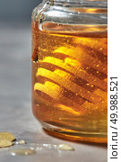 Honey background with natural flower yellow honey in glass pot with wooden dipper, traditional pure natural sweet goodness.. Close-up view of glass jar with golden honey and wooden dipper on a gray background. Jewish New Year healthy holiday . Стоковое фото, агентство Ingram Publishing / Фотобанк Лори