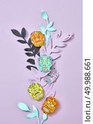 The pattern of handcraft paper Calaveras attribute of the Mexican holiday of Calaca and colored leaves on a purple background with space for text. Layout to halloween. Flat lay. Handmade craft composition of multi-colored paper leaves and Calaveras attribute of the Mexican holiday of Calaca on a purple background with space for text. Halloween card. Flat lay. Стоковое фото, агентство Ingram Publishing / Фотобанк Лори