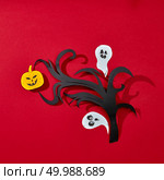 Paper branch, smiling scary pumpkin and ghosts on a red background with reflection of shadows and copy space. Creative handcraft Halloween card. Flat lay. Postcard for Halloween handcraft of paper ghosts and pumpkins with scary faces on a branch presented on a red background with reflection of shadows and space for text. Flat lay. Стоковое фото, агентство Ingram Publishing / Фотобанк Лори