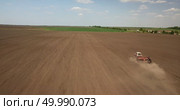 Farmer in tractor preparing land with seedbed cultivator as part of pre seeding activities in early spring season of agricultural works at farmlands. Drone photo. Farmer in tractor preparing land with seedbed cultivator against the blue sky. Стоковое фото, агентство Ingram Publishing / Фотобанк Лори