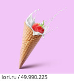 Natural refreshing fruit ice cream cone ads with splash milk and strawberrie isolated on pink. Healthy dairy product with fresh and ripe strawberry and milk splashes. Natural strawberry ice cream and summer concept. Ice cream waffle cone with milk splash and strawberry isolated on pink. Стоковое фото, агентство Ingram Publishing / Фотобанк Лори