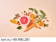 Natural organic citrus fruits, vegetables - ingredients for making homemade detox smoothie on yellow paper background with copy space. Flat lay. Carrot, slices of orange and grapefruit, mandarins, almonds, green leaf on a paper background. Concept of colorful organic food. Стоковое фото, агентство Ingram Publishing / Фотобанк Лори