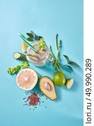 Natural ingredients for healthy smoothie from green vegetables and fruits, flax seeds in glass on a blue with copy space . Concept of vegan and healthy eating.. Green detox smoothies from avocado, selery, cucumber with flax seeds in a glass jar on a blue paper background. Стоковое фото, агентство Ingram Publishing / Фотобанк Лори